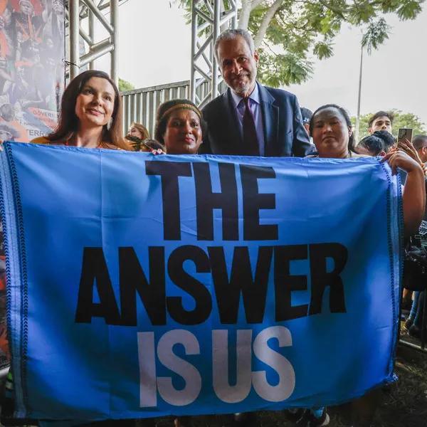 Activists and COP30 representatives holding a banner that says "the answer is us"