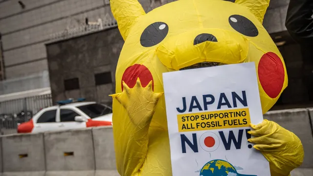 Activist in Pikachu costume holding sign "Japan stop funding fossil fuel"