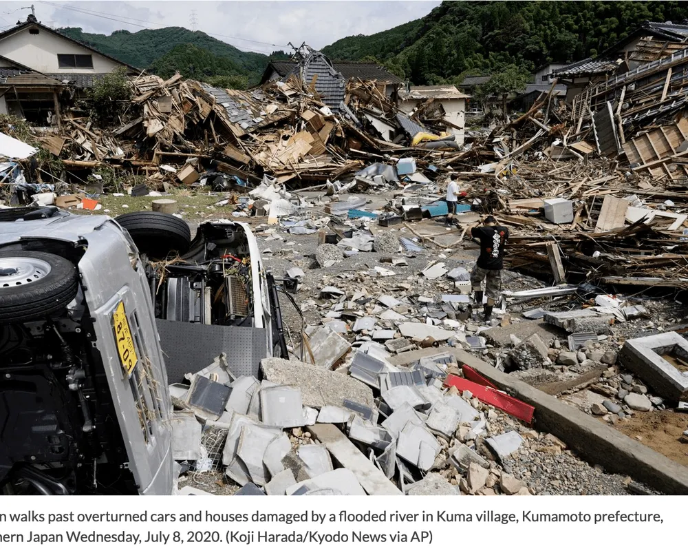 A man walks past overturned cars and houses damaged by a flooded river in Kuma village, Kumamoto prefecture, southern Japan.