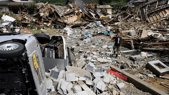 A man walks past overturned cars and houses damaged by a flooded river in Kuma village, Kumamoto prefecture, southern Japan.