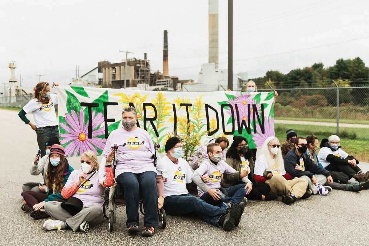 Activists from 350NH sitting and standing in front of banner that says