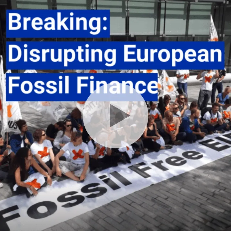 Screenshot from video of action at the EIB with a play button superimposed on it