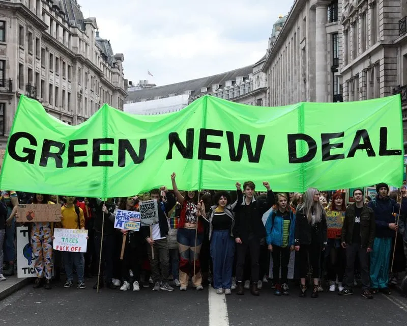 people marching and carrying Green New Deal banner