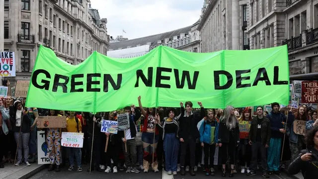 people marching and carrying Green New Deal banner