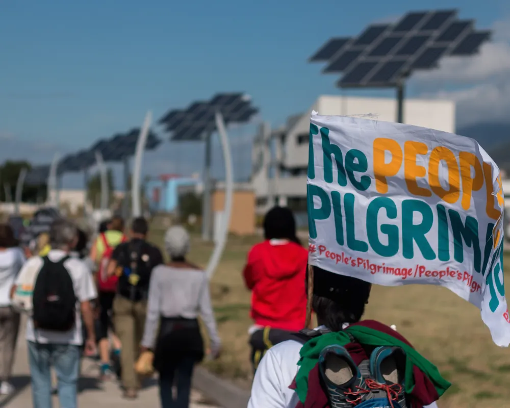 Yeb Saño, the Pilgrims and the Pacific Climate Warriors, walk by solar energy panels.