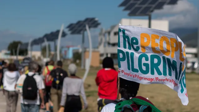 Yeb Saño, the Pilgrims and the Pacific Climate Warriors, walk by solar energy panels.