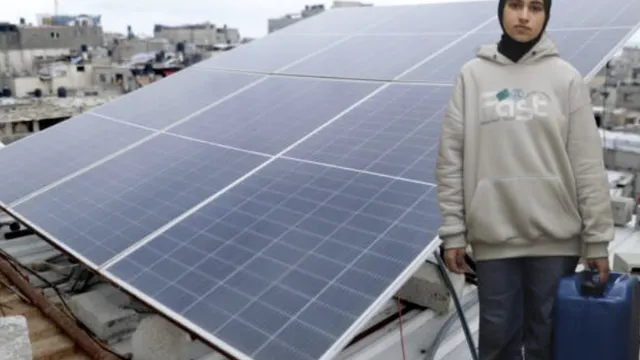 Remas, a 12 year old girl living in Deir Al-Balah camp in Gaza in front of a solar panel
