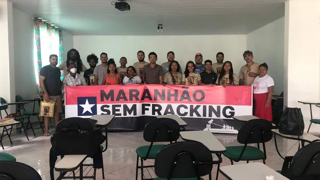 A group of people in a classroom holding a banner that reads "MARANHAO SEM FRACKING" (Maranhao Without Fracking) with a star symbol, advocating against hydraulic fracturing in the Brazilian state of Maranhao.