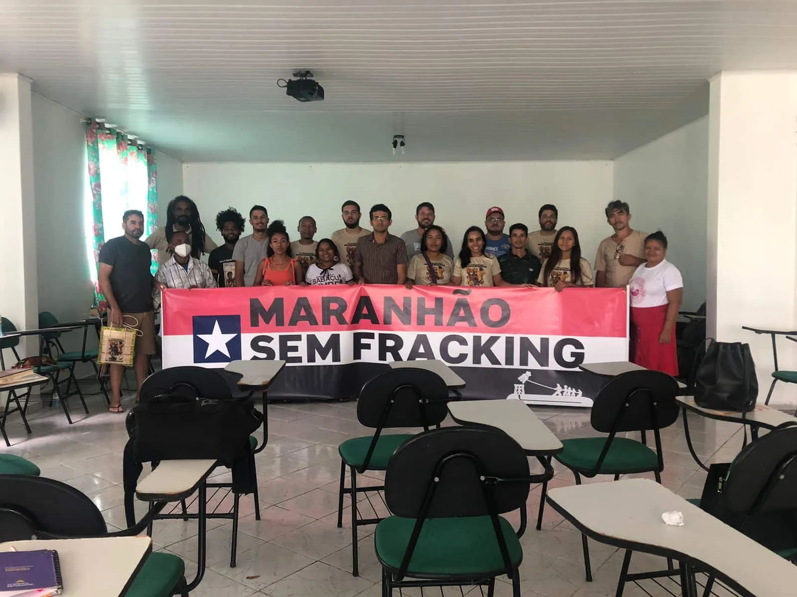 A group of people in a classroom holding a banner that reads "MARANHAO SEM FRACKING" (Maranhao Without Fracking) with a star symbol, advocating against hydraulic fracturing in the Brazilian state of Maranhao.