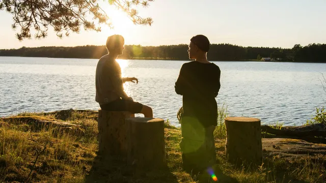 two people having a conversation at sunset near a lake