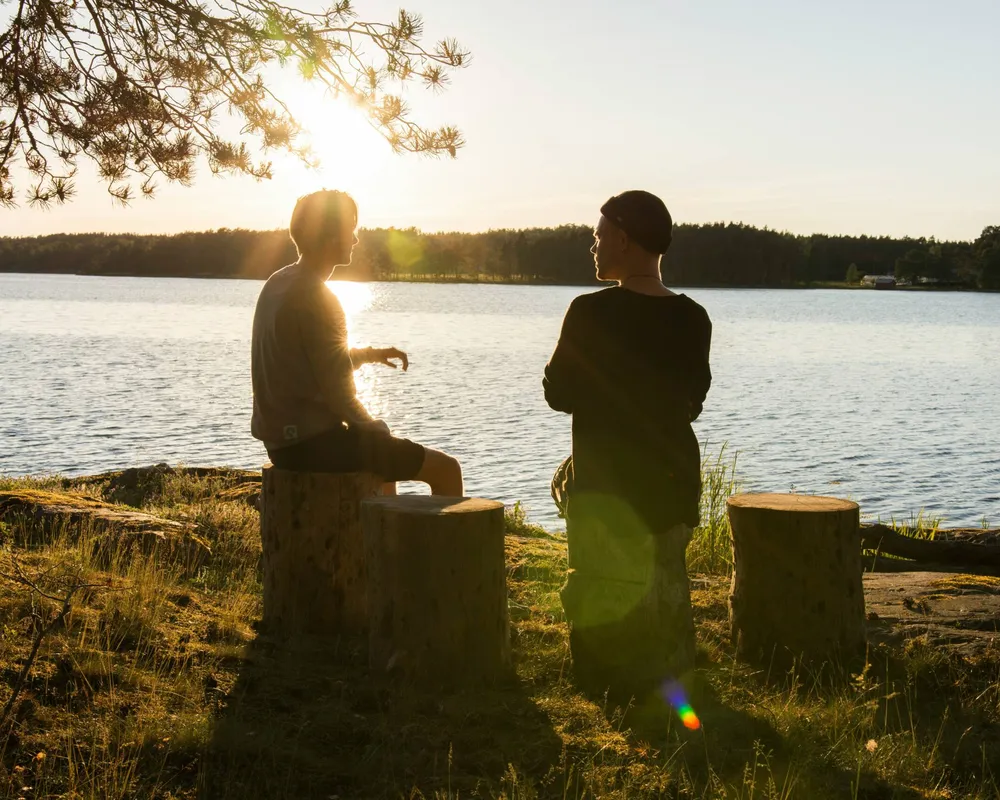 two people having a conversation at sunset near a lake