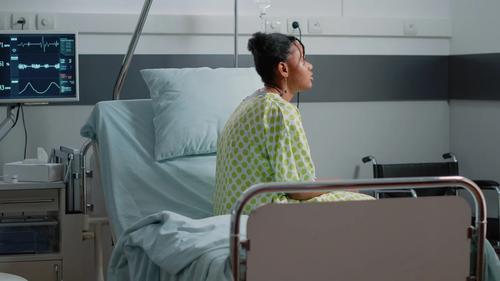 african-american-patient-with-sickness-sitting-hospital-ward-bed-waiting-receive-treatment-medical-assistance-from-doctor-young-woman-with-iv-drip-bag-heart-rate-monitor-1.jpg
