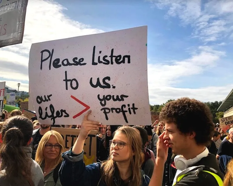 Young people at the Climate Strike in Berlin in September 2019 hold up a banner: "Please listen to us. Our lives > your profit.