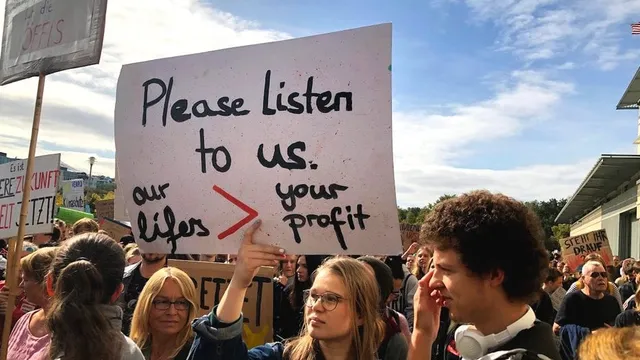 Young people at the Climate Strike in Berlin in September 2019 hold up a banner: "Please listen to us. Our lives > your profit.