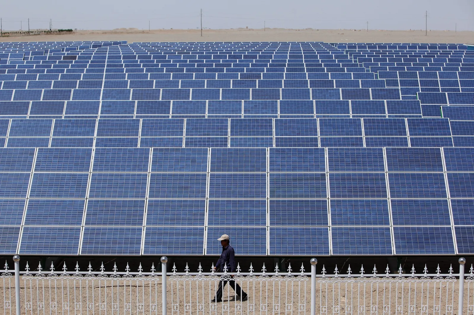 DUNHUANG, GANSU - JULY 21: A Chinese worker walks near the solar modules of a newly installed 100MW photovoltaic on-grid power project on July 21, 2010 in Dunhuang of China's northwest Gansu Province. The government is tendering for bids to develop 13 solar projects with a combined capacity of 280MW in the western regions. The Chinese government has set a target to install 20GW of solar energy capacity and 100GW of wind power by 2020. (Photo by Feng Li/Getty Images)