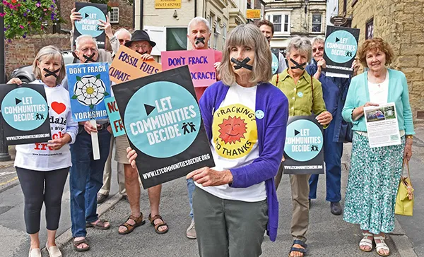 Eight elderly activists hold anti-fracking signs