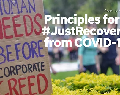 A sign reads human needs before corporate greed with a title saying Principles for a Just Recovery from COVID-19