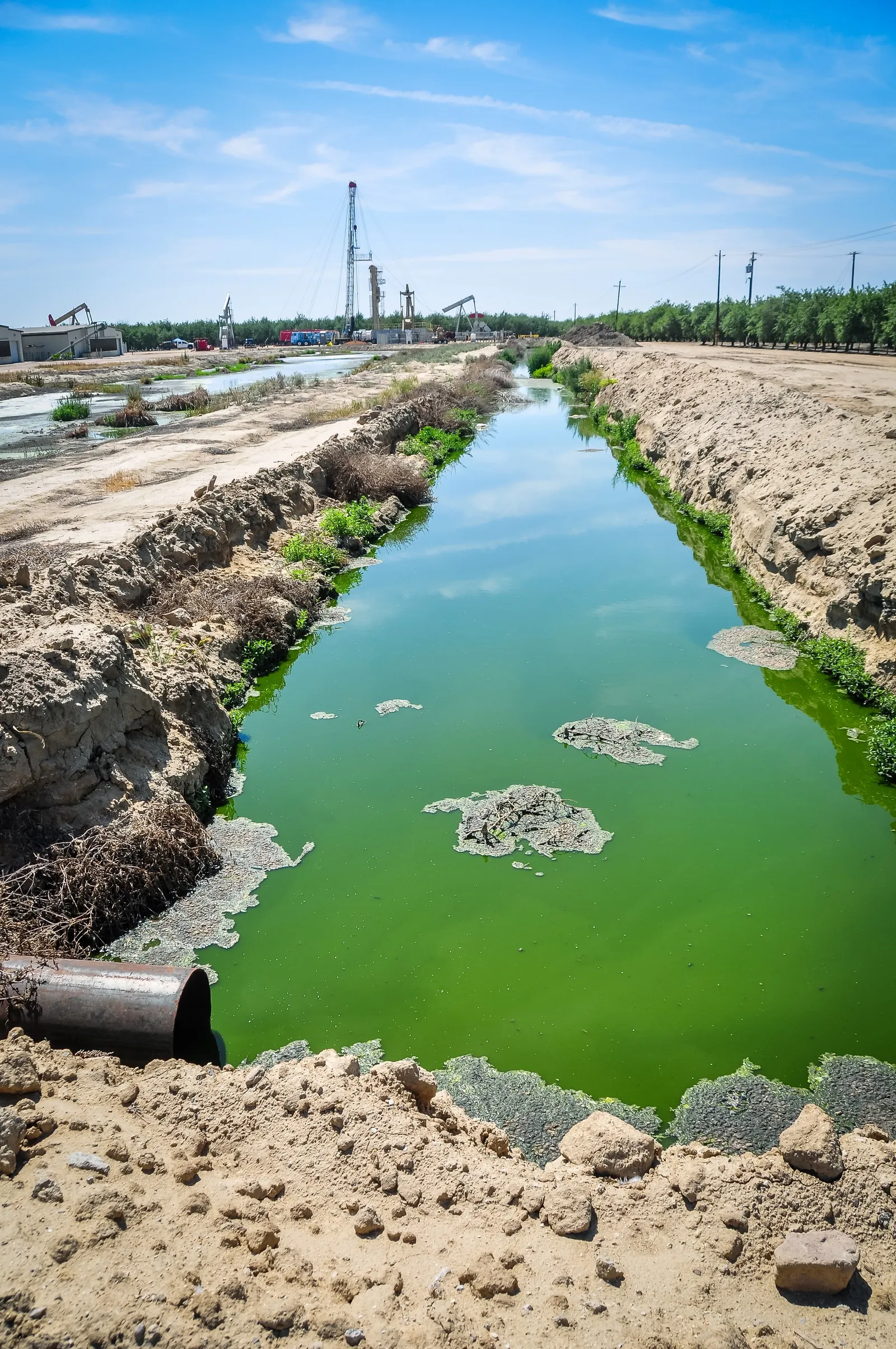 Unlined pit of unidentified fluid leading up to a fracking well. Shafter, CA