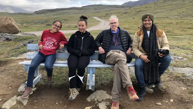 photo of four of the documentary team sitting on a bench in a wild landscape