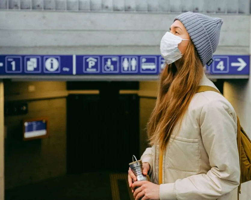 A woman wearing a facemask at the entrance to metro station