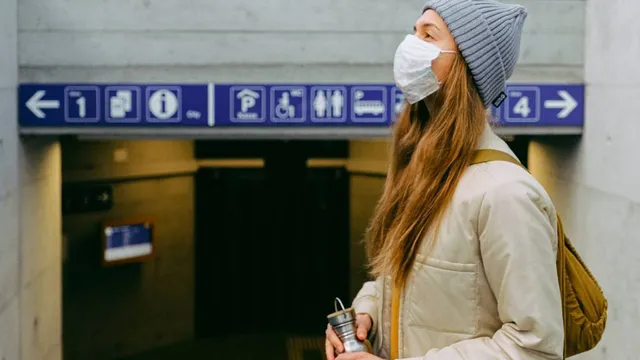 A woman wearing a facemask at the entrance to metro station