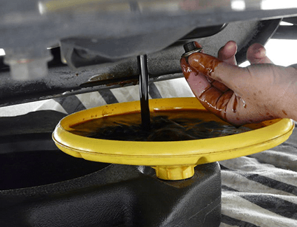 The old oil is drained out from this vehicle and into a drip pan for safe disposal