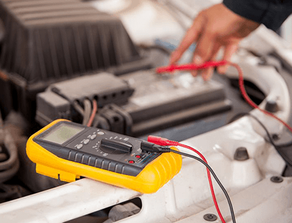 Closeup of multimeter being used to test car battery