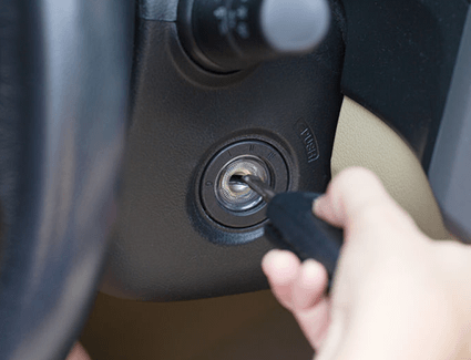 Hand inserting a car key into the ignition to start a vehicle