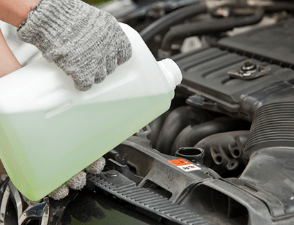Person adding coolant to a vehicle