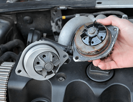 A person holds an old water pump next to a new one.