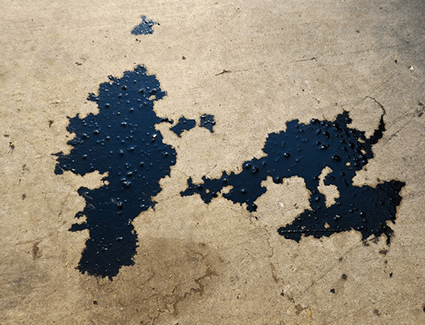 Two large puddles of oil on pavement Two large puddles of oil on pavement