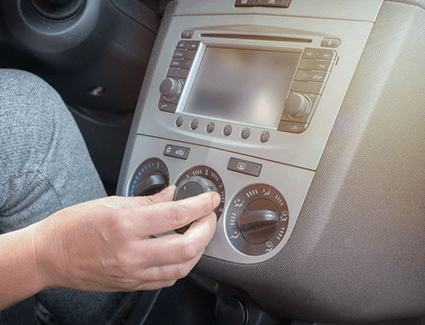 A person adjusts their car air conditioning settings.