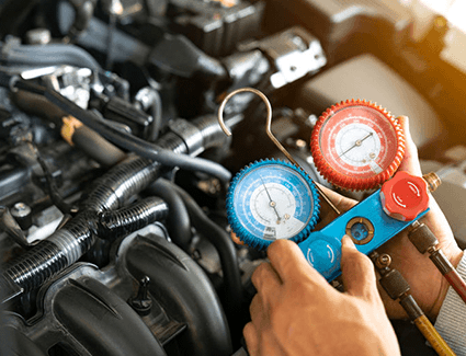 A technician uses automotive air conditining gauges to put the right amount of refrigerant back into the system A technician uses automotive air conditining gauges to put the right amount of refrigerant back into the system