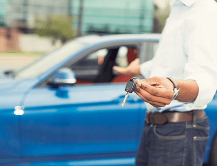 Person holding keys in one hand and gesturing to a car with the other