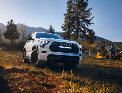 Photograph of a 2023 Sequoia in Ice Cap White parked next to a campsite.