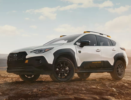 Exterior view of a white all-new 2026 Subaru Crosstrek driving in the dirt