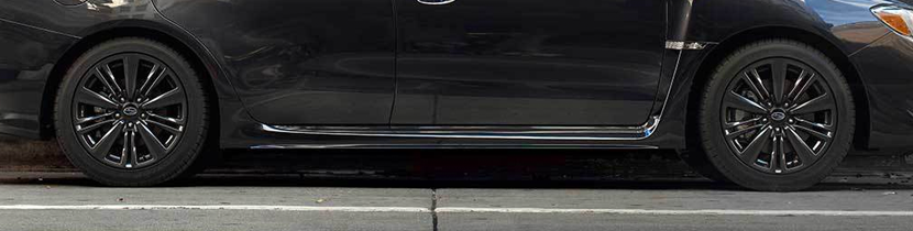 Side-view photograph of the lower half of a black sedan.
