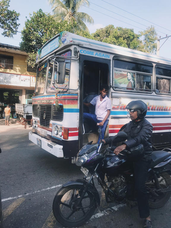 guy hanging on the outside of bus in Sri Lanka