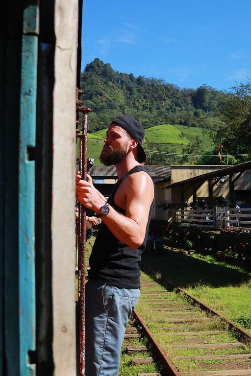 tourist hanging on the outside of train in Sri Lanka