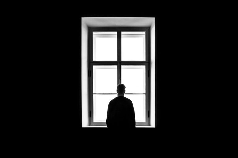 Man standing at a window thinking