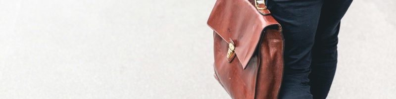 person walking holding brown leather bag