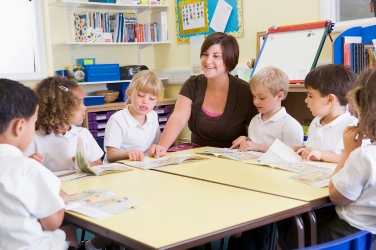 99939230 Teacher reading at desk with children