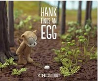 Picture book of teddy bear looking at an egg in the forest
