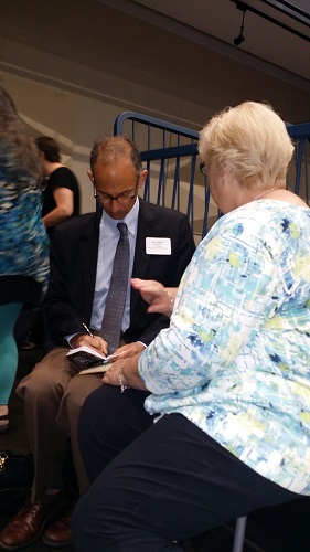 After his keynote, the crowd approaches Dr. Needlman with questions, and he takes notes. 