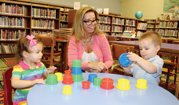 Twins stacking cups at the North Bellmore (NY) Public Library with Renee McGrath, manager of youth services for the Nassau (NY) Library System. Photo by Michele Rudzewick.