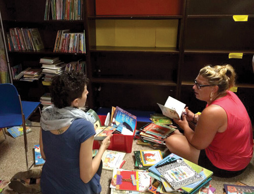 In Baltimore, Patricia Rickle (left) and Julia Malanka, volunteers with UFPIA, sort books at the the new Wolfe Street Academy reading area. Courtesy of Mollie Fein