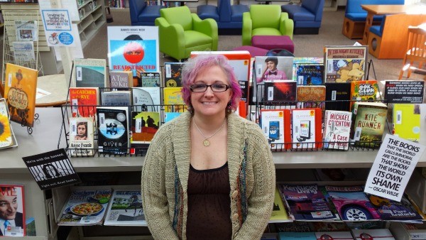 Jama Watts proudly poses in front of her banned books display.
