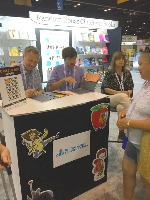 Lane Smith (left) and Jory John (right) team up on personalizing copies of their Penguin Problems at the Random House booth