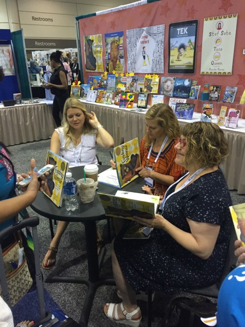 Author Lindsay Mattick (in white) and illustrator Sophie Blackall (in red) signing Finding Winnie at the Hachette booth