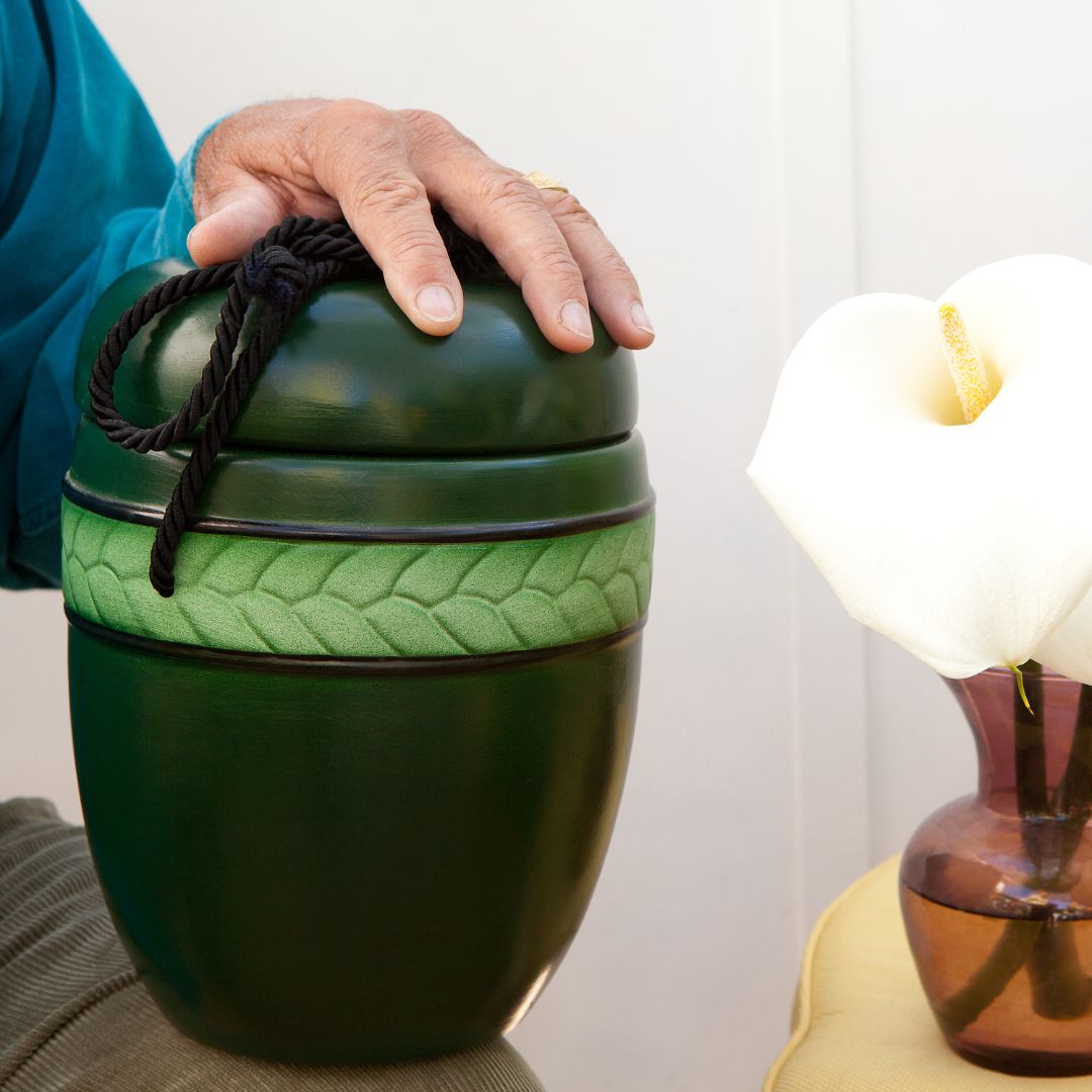 a person holding a green urn